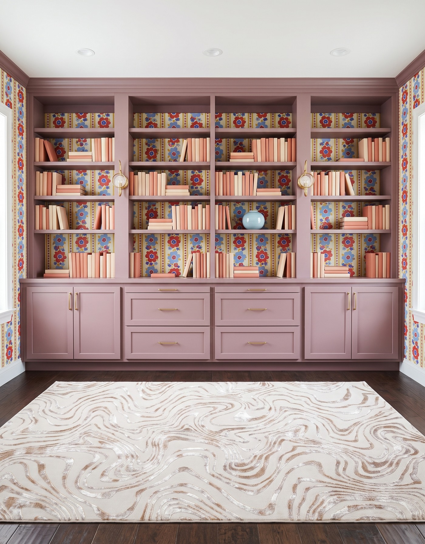 Library with dusty mauve framed cabinets, red-and-blue floral-striped wallpaper on cream, dark brown wood floor, cream-and-taupe contour rug, brass circular glass sconces and coral-and-cream books.