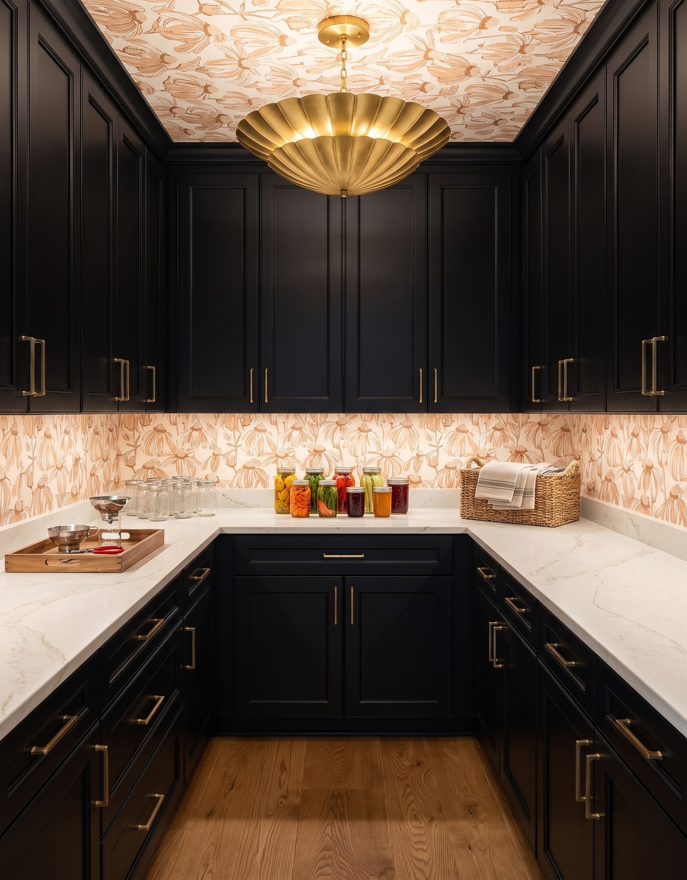 AI-created concept: Black pantry cabinets beneath a warm cream botanical ceiling, with pale counters, preserving jars and a gold scalloped light.