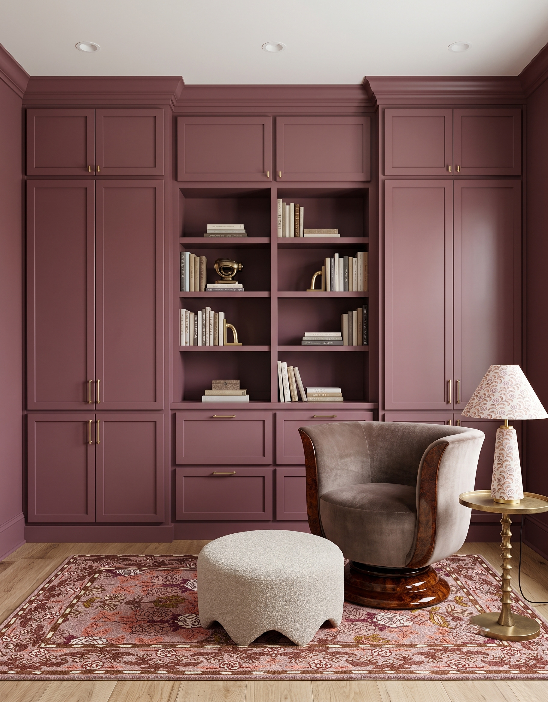 Muted plum built-in cabinets around central bookshelves, with a curved wood-trimmed chair, pale scalloped ottoman and patterned rug.