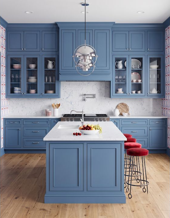 Concept image of a blue kitchen with a medium wood floor, pale island, glass-front cabinets, and bright red counter stools.