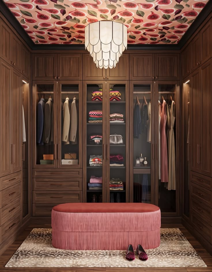 Walnut closet cabinetry mixing hanging, drawers, shelves, and a pink upholstered bench.