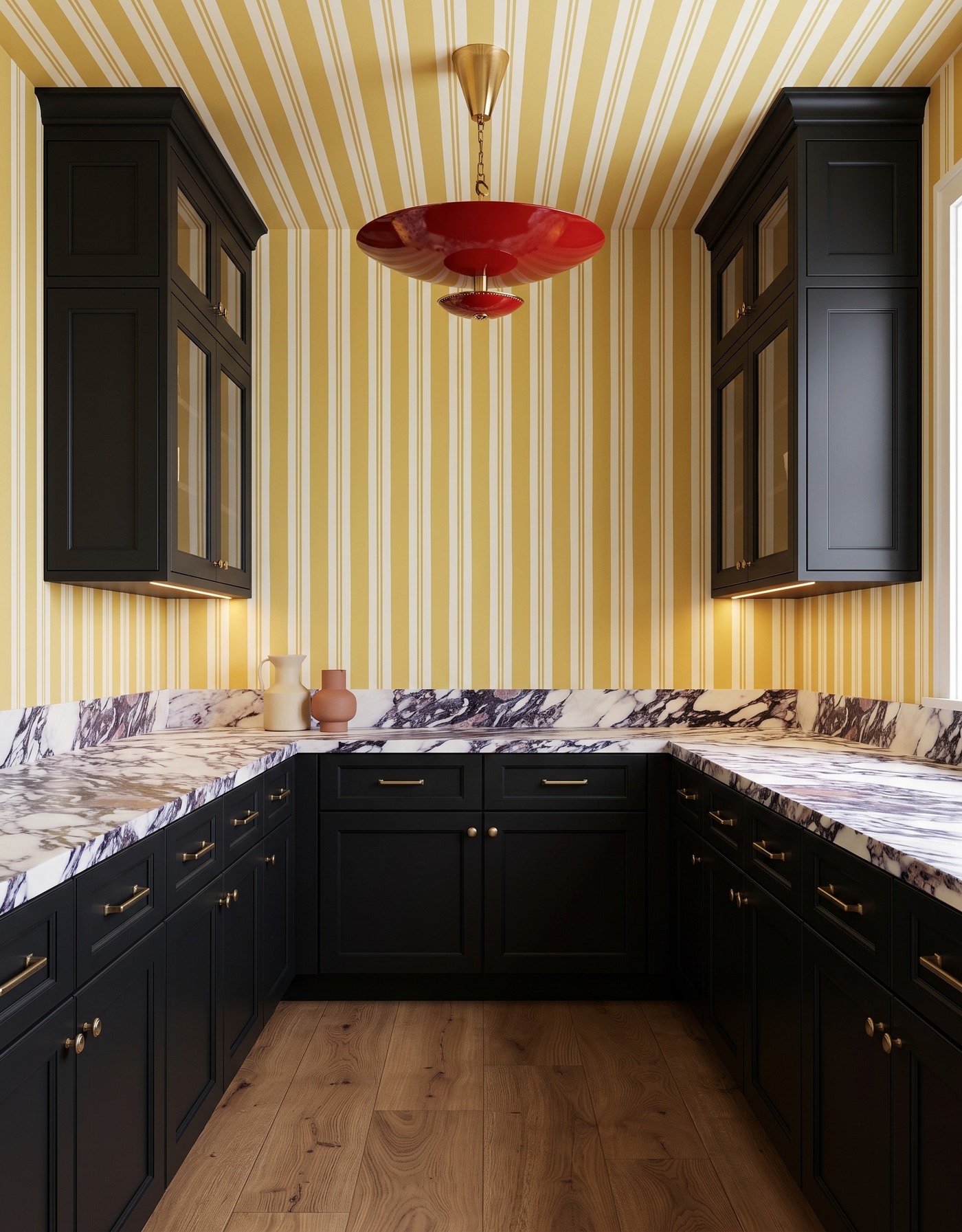 Pantry with black cabinets, mustard-and-ivory striped wallpaper, white counters with charcoal and plum veins, warm tan wood floor and red saucer pendant.