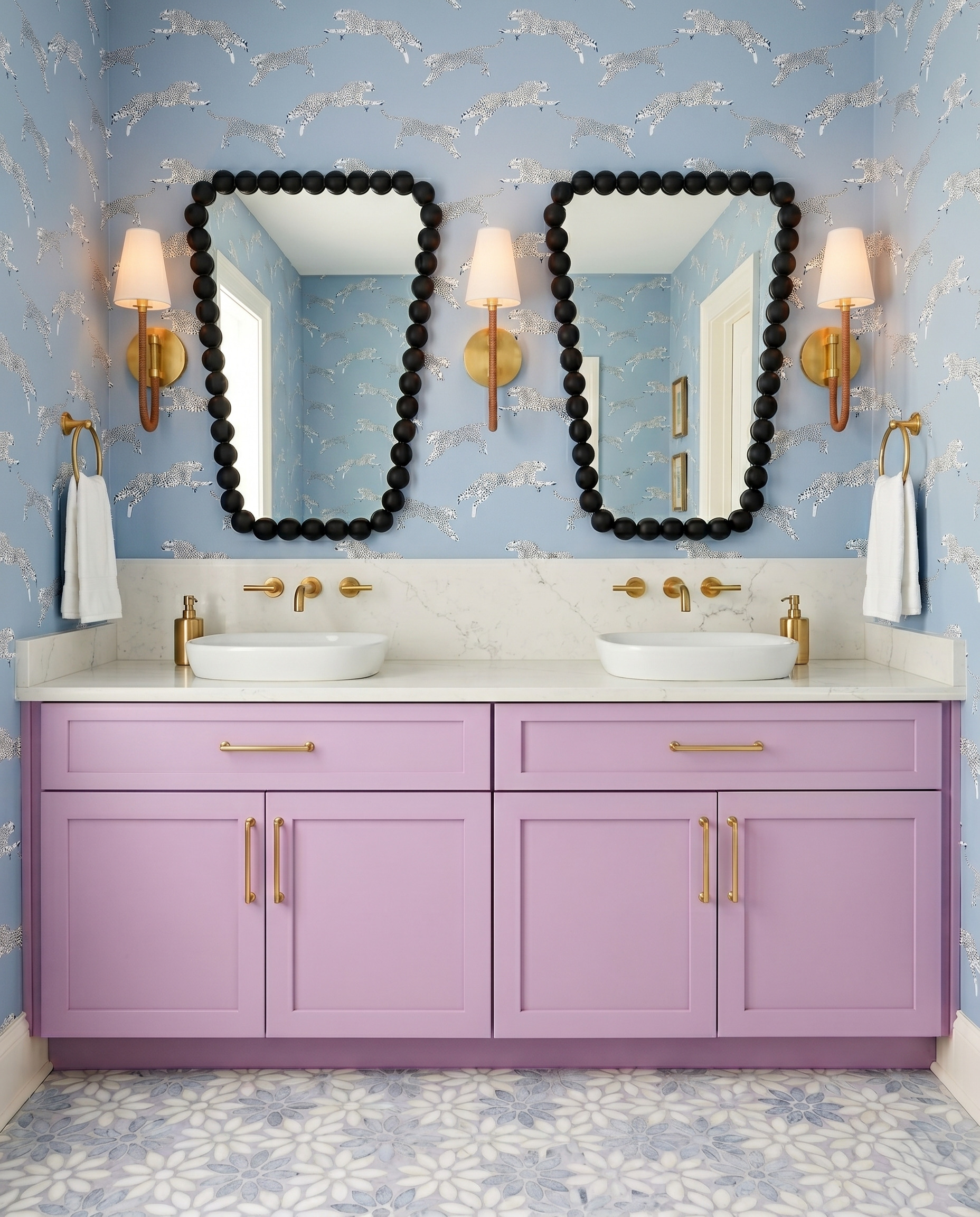 Lavender double vanity with white vessel basins, powder-blue animal-print wallpaper and black beaded mirror frames.