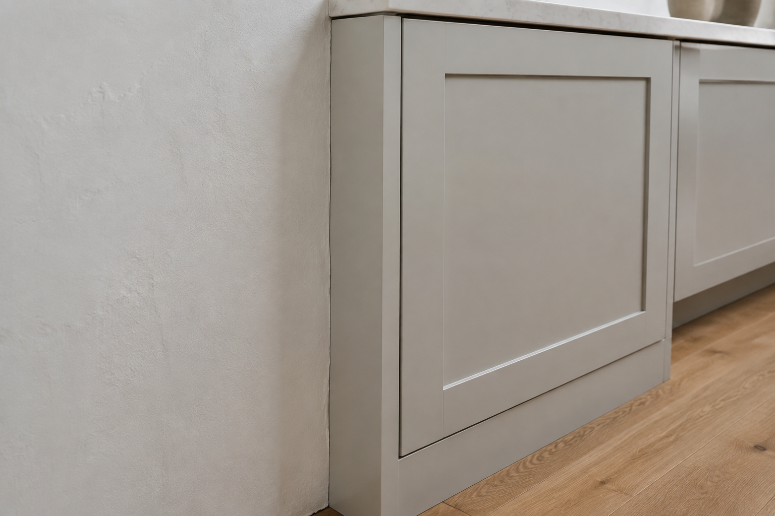 A narrow painted filler strip is scribed to an uneven wall beside a closed cabinet door with a clean, usable reveal.