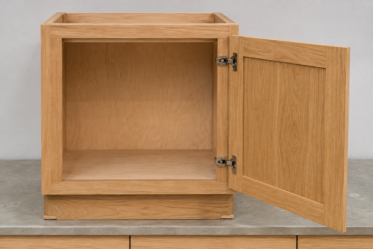 Complete empty natural-oak face-frame base cabinet with a solid door attached to the visible front frame by two concealed hinges.