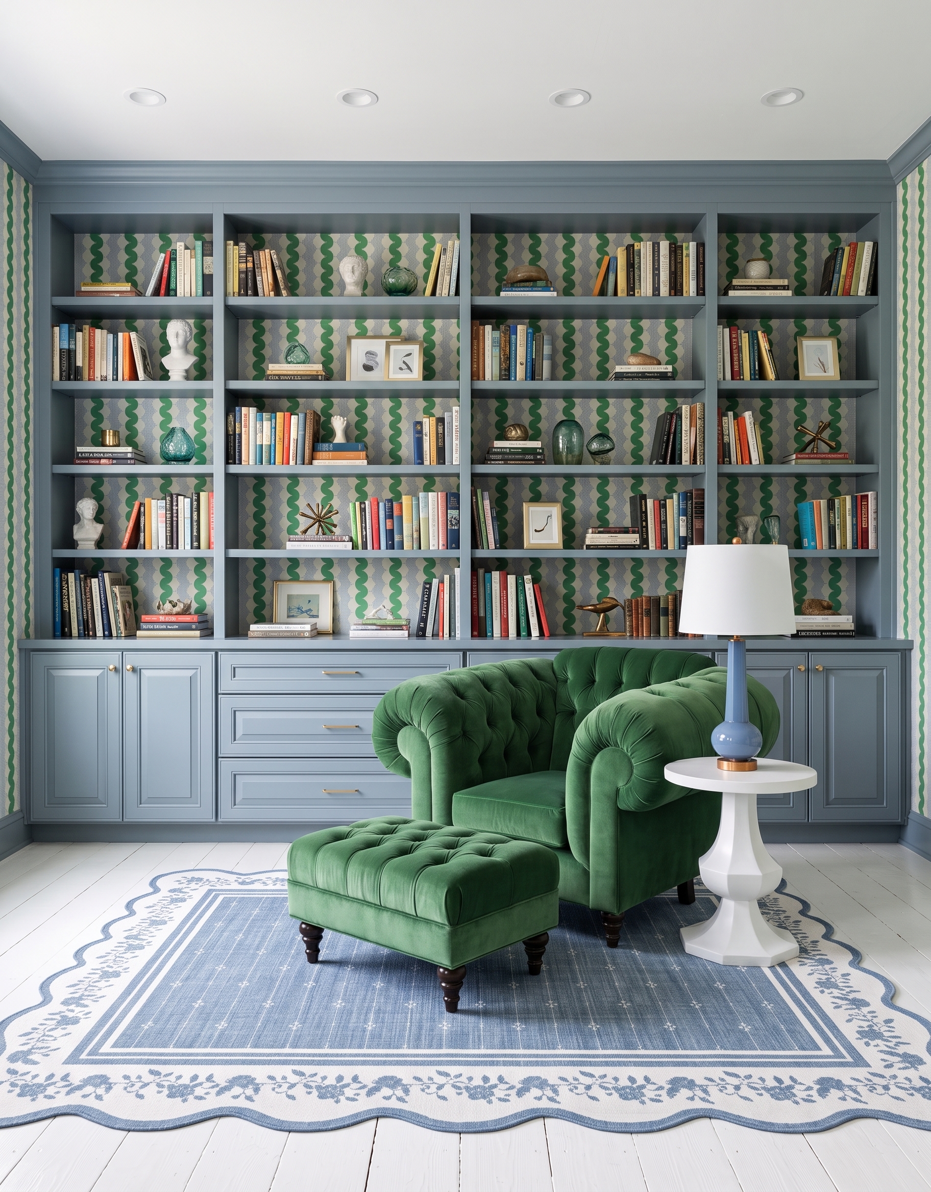 Powder-blue library concept with green wavy wallpaper, a tufted green chair and ottoman, a blue table lamp and a scalloped blue-and-white rug.