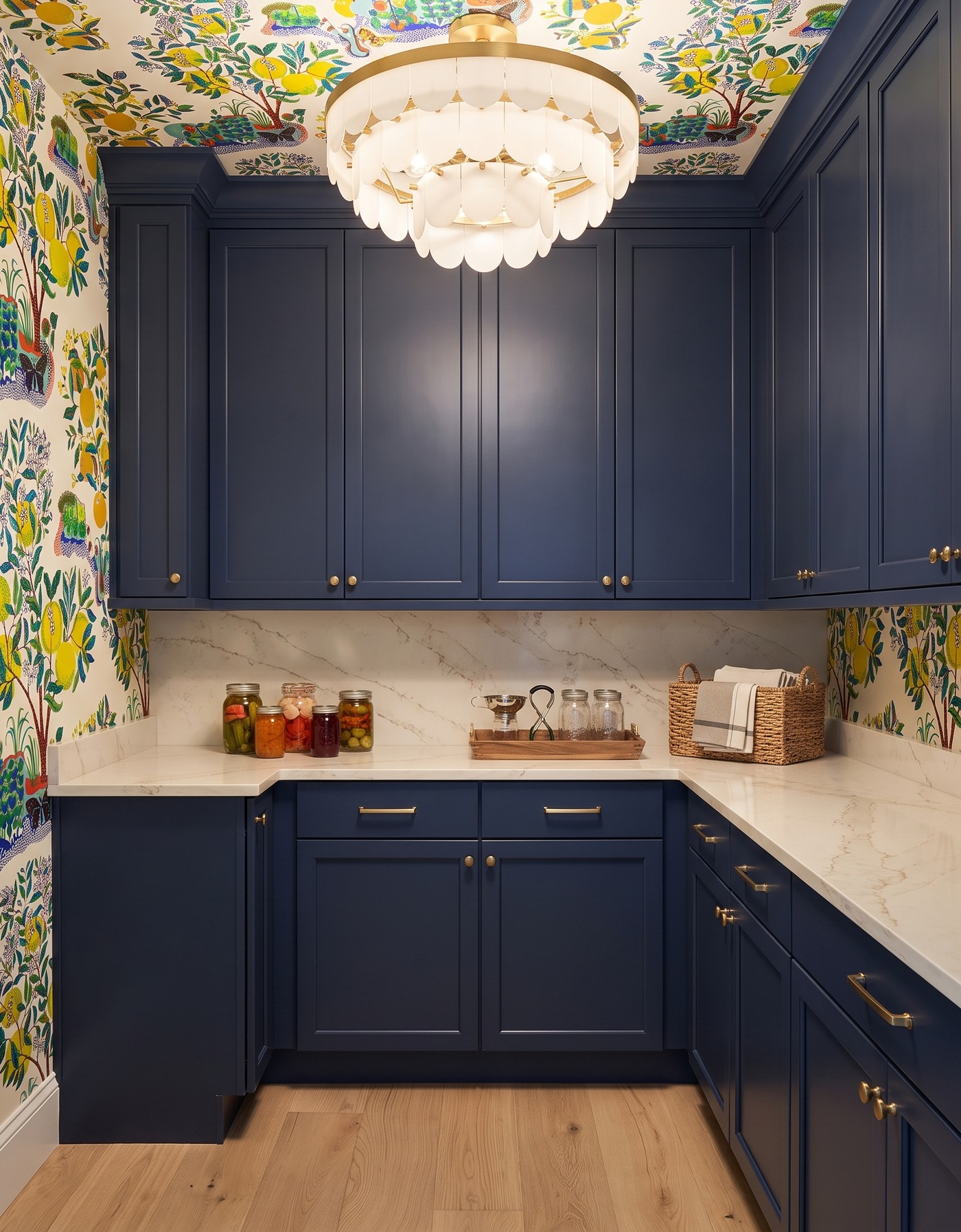AI-created concept: Deep-blue pantry cabinets with citrus-tree wallpaper, pale counters, preserving jars and an ivory scalloped light.