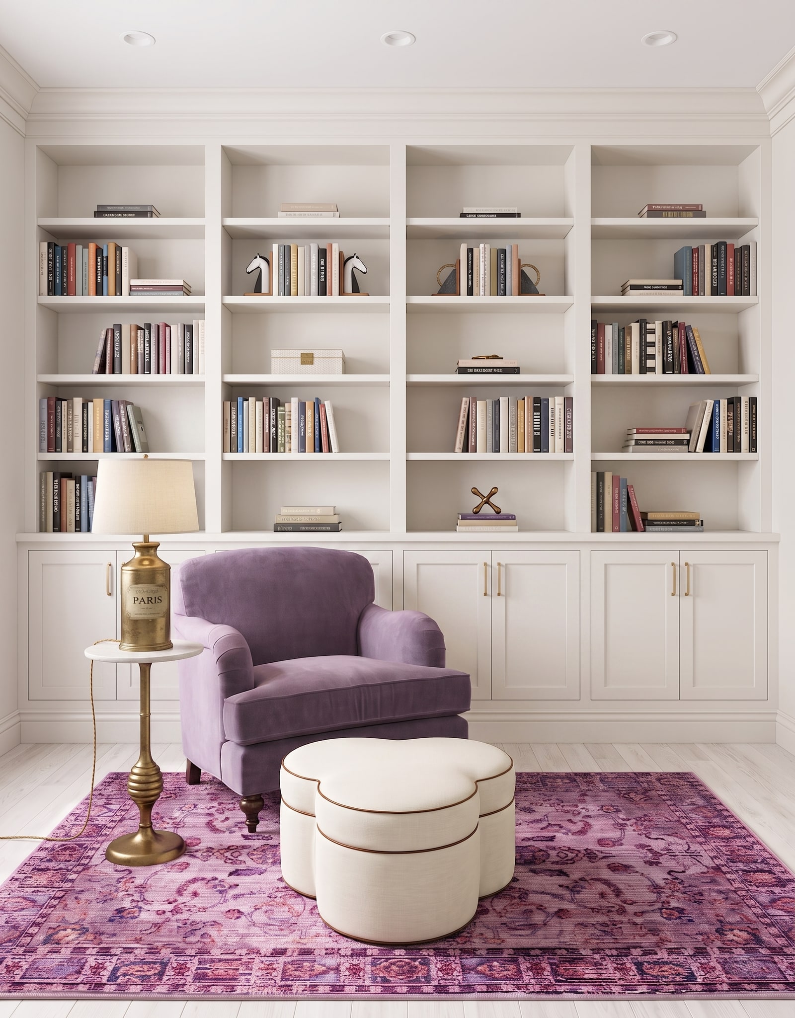 A white wall-to-wall bookcase with evenly divided shelf bays, closed base cabinets, and a purple reading chair.
